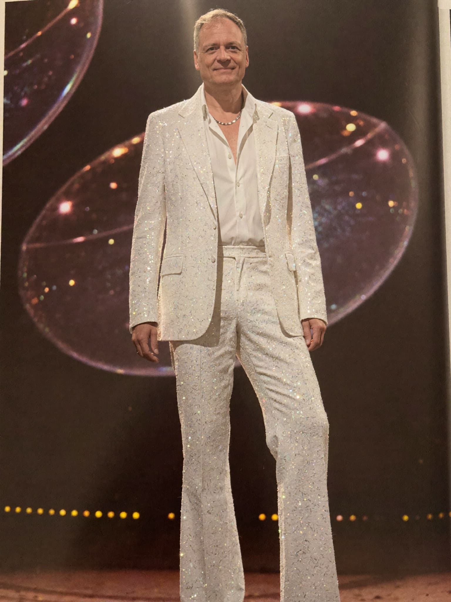 ABBA Voyage costume — White sequined suit with bell-bottom flares.